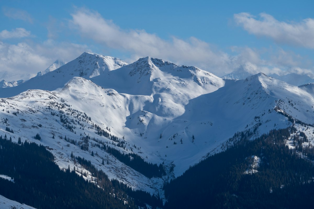 Snow-covered Alpine peaks under a blue sky
